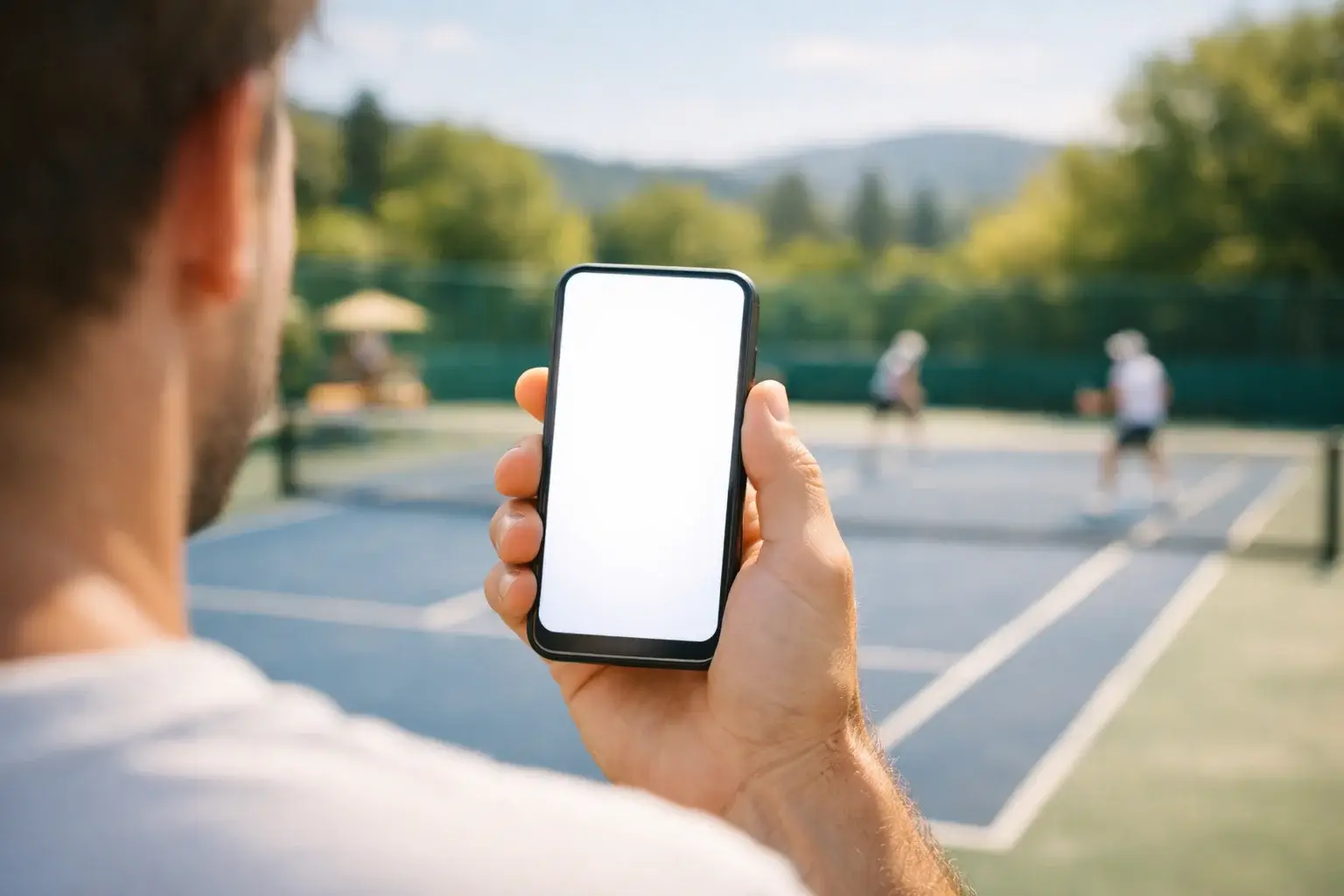 Mano che tiene uno smartphone davanti a un campo da tennis durante una partita di doppio